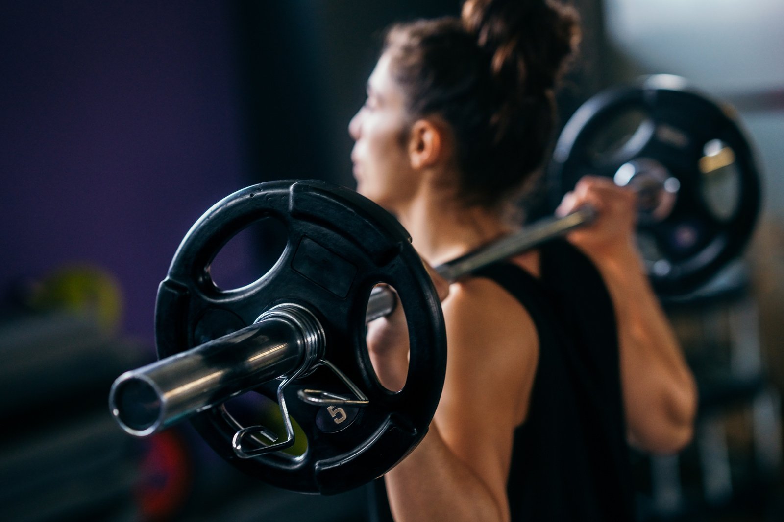 Athletic woman in gym lifting weights at the gym